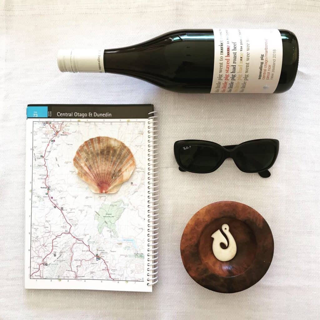New Zealand wine, roadmap, sunglasses, and fish hook necklace--plan the perfect New Zealand vacation