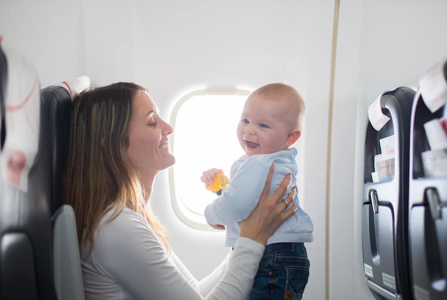 Young mom playing with baby on airplane.