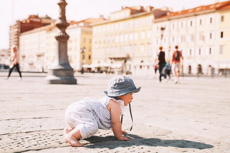 Baby girl crawling on a european city street in Trieste, Italy, Europe. 