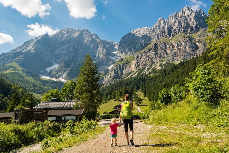 Rear view of mother and daughter hiking a picturesque mountain valley in Austria.