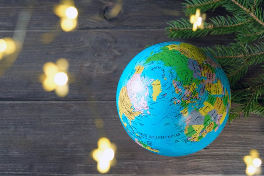 Globe, spruce branches and Christmas lights against rustic background.