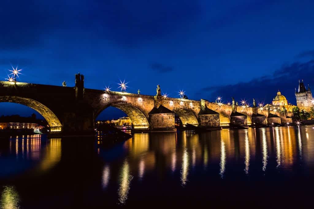 Stunning night view of the illuminated Charles Bridge reflecting in the Vltava River in Prague, Czech Republic.